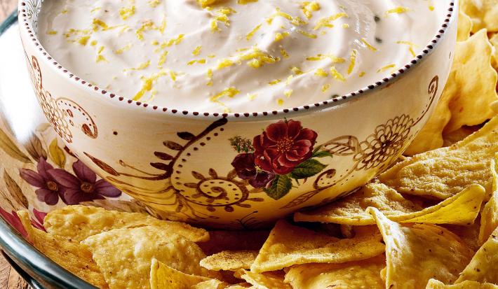 fotografia em tons de marrom e branco tirada de uma bancada vista de frente. Contém um recipiente com biscoitos, e um recipiente redondo branco por cima com um creme.
