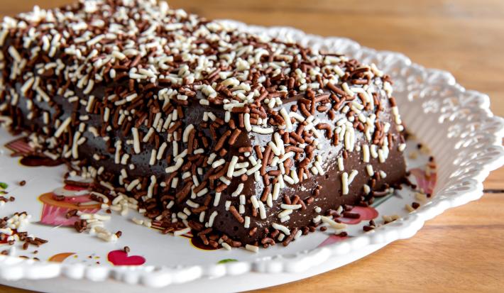 Imagem da sobremesa retangular coberta com chocolate granulado branco e preto.