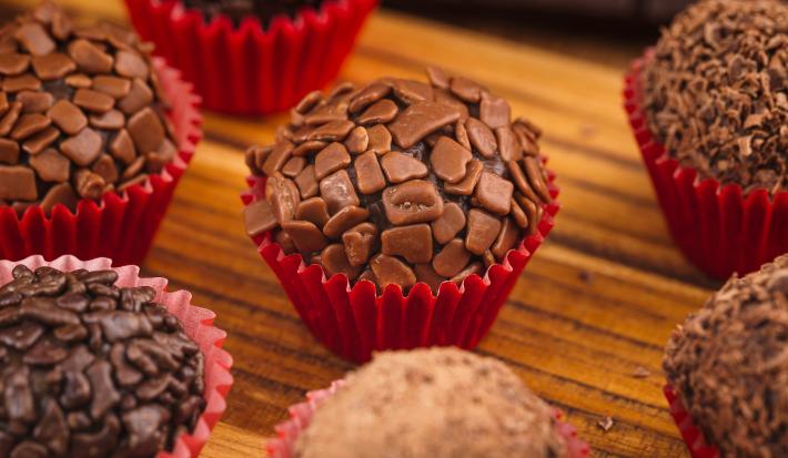 Imagem aproximada de brigadeiros gourmet em forminhas vermelhas.