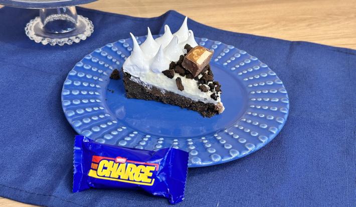 Fotografia em tons de azul com um prato azul ao centro. Dentro do prato existe uma fatia de torta feita com Recheio CHARGE, biscoito NEGRESCO e mousse de Limão