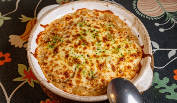 Em uma mesa, prato redondo com queijo gratinado.