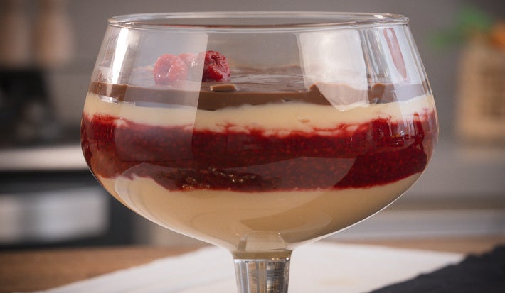 Taça com bombom de framboesa. O doce tem três tipos de camadas: brigadeiro branco, geleia de framboesa e chocolate.