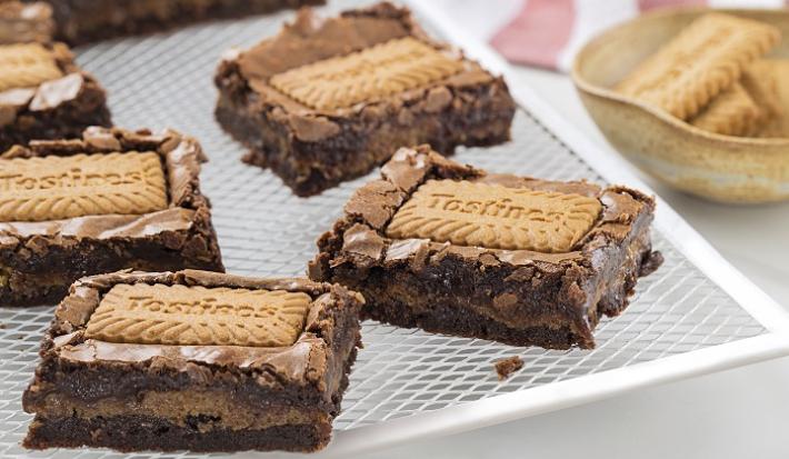 Foto da receita de Brownie de Tostines. Observa-se 5 fatias de brownie com o Biscoito TOSTINES Especiarias em cima e recheado de creme.