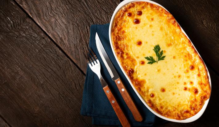 Fotografia mostra uma torta dourada, com a mussarela derretida e gratinada a coentro decorando.