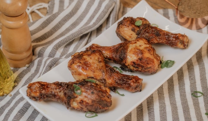 Imagem de coxas de frango douradas feitas na air fryer sobre um prato retangular branco.
