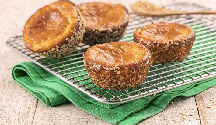 Foto da receita de Muffin Funcional. Observa-se quatro muffins desenformados dispostos sobre uma grade, que está em cima de um guardanapo verde. Atrás, uma pequena colher de madeira.