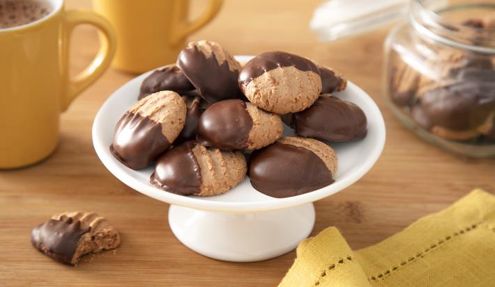 Foto da receita de Biscoitinho de Cappuccino. Observa-se uma boleira branca com 8 biscoitinhos em cima, banhados pela metade com chocolate.