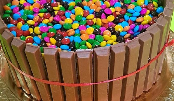Foto em tons de marrom da receita de bolo de cerquinha decorado com confetes coloridos servida sobre uma base prateada
