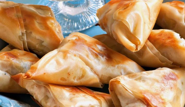 fotografia em tons de azul e bege tirada de uma prato quadrado azul com Samosas de massa filo.