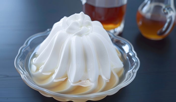Em cima de uma mesa, recipiente com beijo gelado branco de coco.