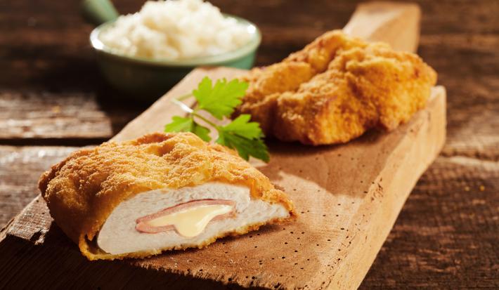 Foto da receita de Filé de Frango à Cordon Bleu. Observa-se um filé de frango cortado ao meio, expondo o recheio de presunto e queijo derretido.