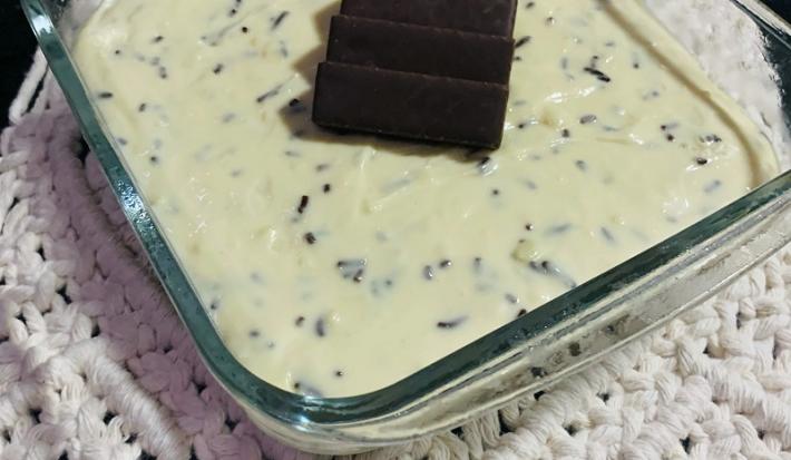 Foto em tons de branco da receita de moça gelada servida em uma travessa de vidro retangular sobre um paninho bordado
