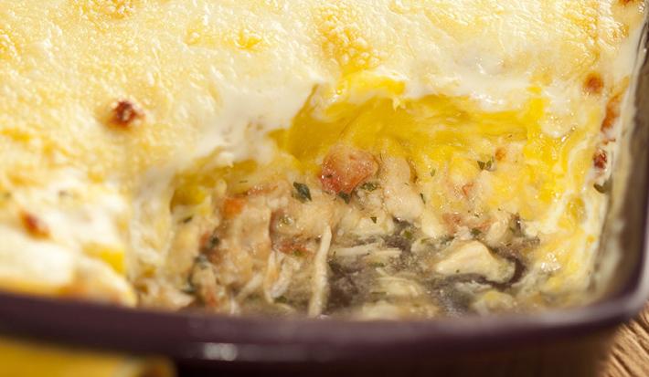 em um recipiente quadrado marrom contém frango desfiado coberto com purê de mandioquinha