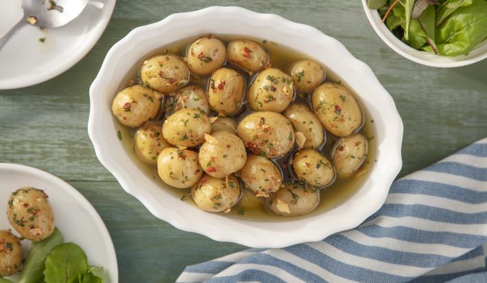 Imagem vista de cima de uma travessa branca com mini batatas temperadas