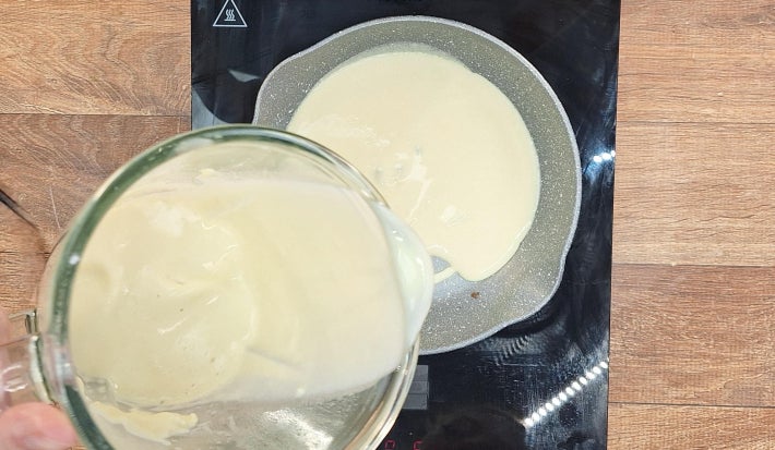 Massa de panqueca fritando em frigideira sobre fogão portátil