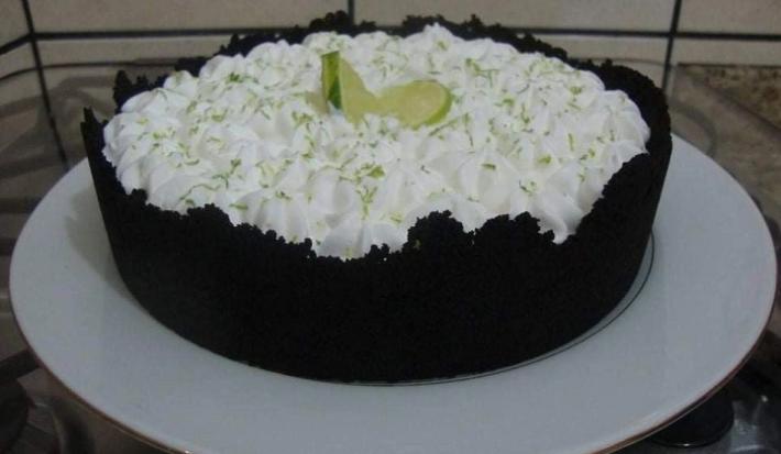 Foto da receita de Torta de Limão com Biscoito. Observa-se uma torta com base escura de chocolate em um prato branco.