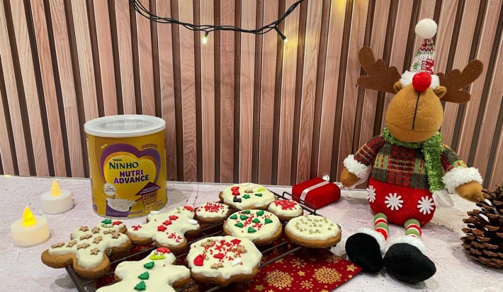 Fotografia em tons de vermelho com uma bandeja de biscoitos natalinos decorados ao centro.