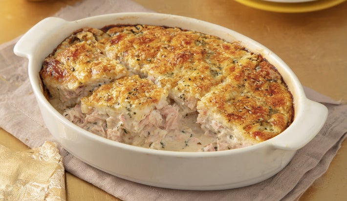 Caçarola assada de atum e salmão em molho cremoso, com superfície dourada gratinada, servida em refratário oval branco.