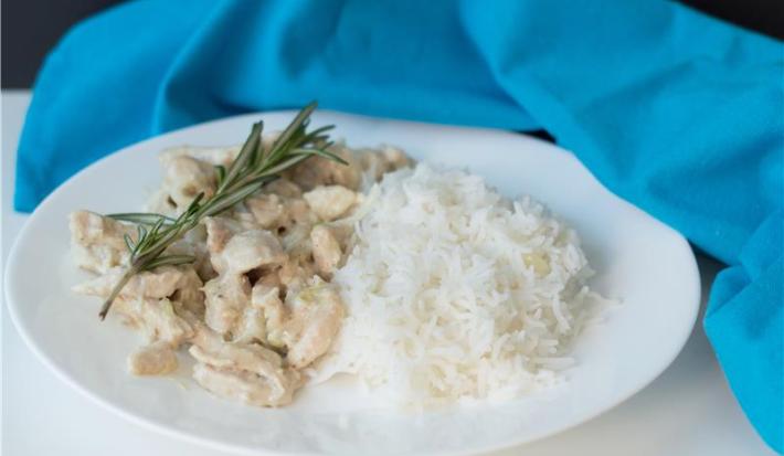 A imagem mostra um prato montado com arroz e tiras de frango com molho, decorado com alecrim