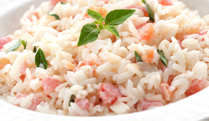 foto em tons de branco e vermelho tirada de um prato redondo branco com arroz e tomate