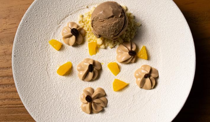 Receita de Café, Cardamomo e Laranja, delicioso e diferente, feito com Bolo de Amêndoa, Caramelo, Mousse de Laranja, Ganache Montada, Sorvete, Crumble Branco e decorado com Chocolate Branco