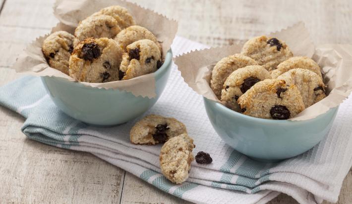 Fotografia em tons de branco e azul de uma bancada branca com um paninho azul e branco, sobre ele dois recipiente redondos azuis com biscoitinhos.