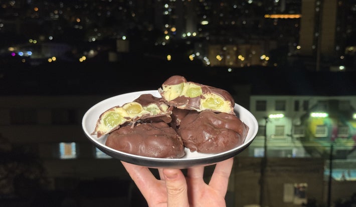 imagem mostra vários bombons de chocolate, um cortado ao meio com um creme branco e uma verde recheado