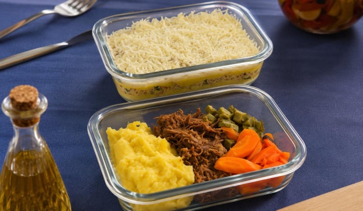 Fotografia de duas marmitas de vidro com receitas de escondidinho de frango e também de carne desfiada com legumes
