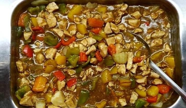 Foto da receita de Frango Xadrez. Observa-se um recipiente refratário com a receita dentro de frango e legumes com molho à base de shoyu.