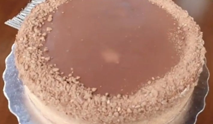 Fotografia de uma torta de chocolate com morangos sobre um apoio de metal.
