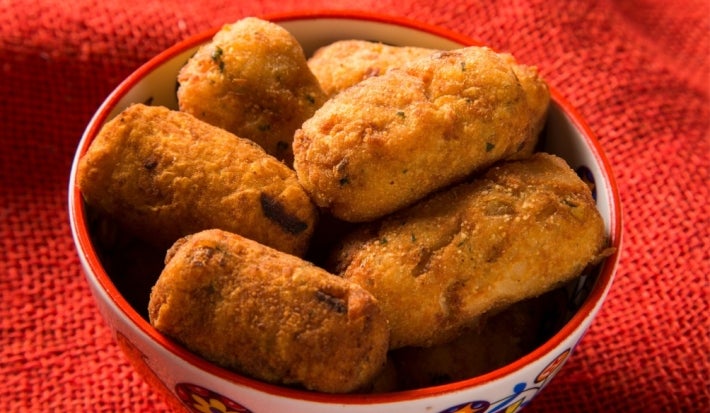 Foto aproximada da receita de Bolinho de Pirarucu, servido em um pote sobre uma toalha vermelha