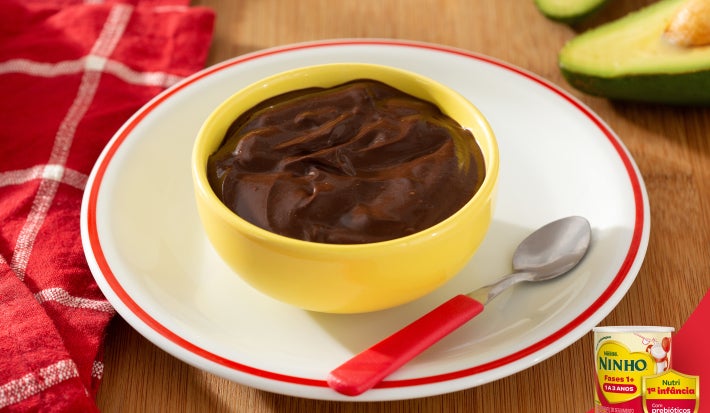 Mousse de chocolate em tigela amarela sobre prato branco com NINHO® Primeira Infância.