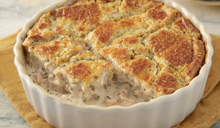 Caçarola cremosa assada com frango e molho branco, gratinada com superfície dourada, servida em refratário branco.