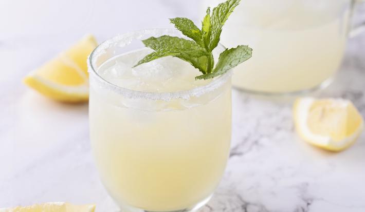 fotografia em tons de branco de uma mesa de mármore. Contém dois copos transparentes com a limonada.