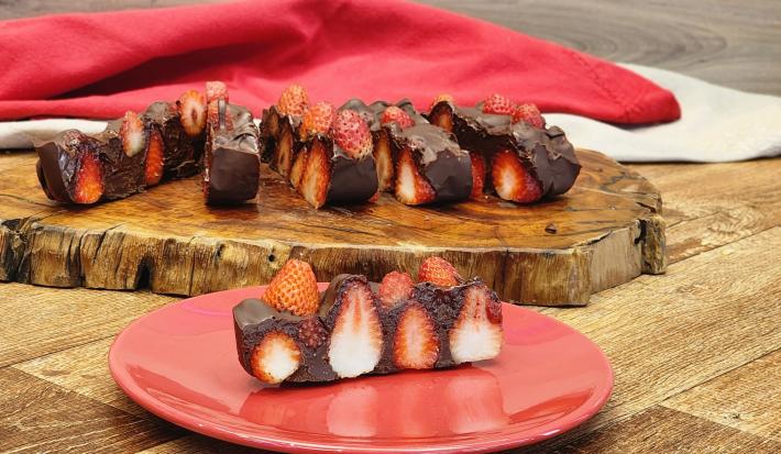 Fotografia de uma barrade chocolate com morango sobre uma superfície de madeira.