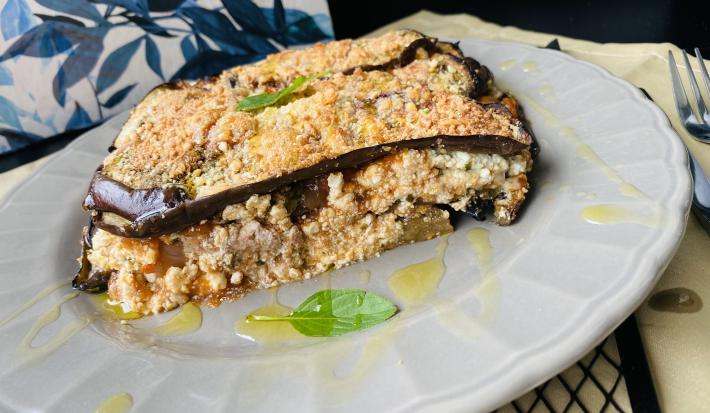 Imagem da receita de Lasanha Nutritiva, em um prato branco, sobre uma mesa, ao lado talheres