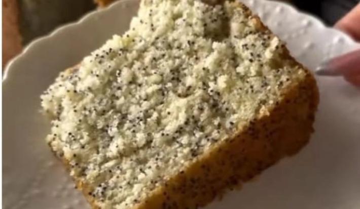 Fotografia de uma fatia grande de bolo de chia com limão sobre um prato branco.