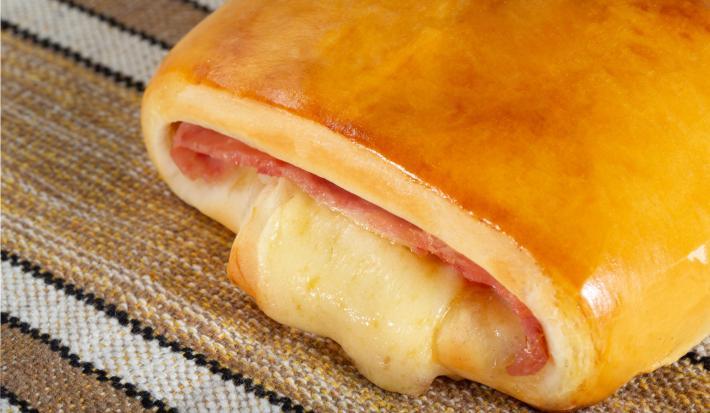 Fotografia de uma receita salgado chamado joelho, recheado com presunto e queijo derretido.