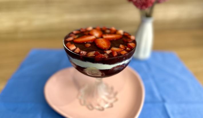 Fotografia em tons de rosa e azul com uma taça de vidro ao centro. Em cima da taça existe uma receita de açaí com frutas e ASCENDA
