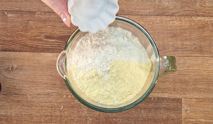 Farinha de trigo, fubá e fermento dentro de liquidificador cobrindo os ingredientes secos