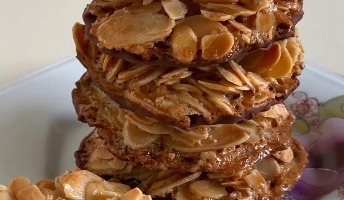 Fotografia de vários biscoitos de amêndoas com chocolate sobre um prato branco florido.