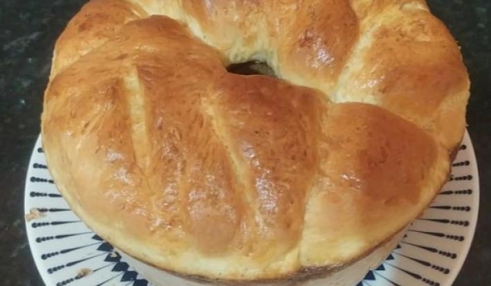 Foto da receita de pão de cebola em uma porção inteira servida sobre um prato de porcelana branco em cima de uma mesa de mármore
