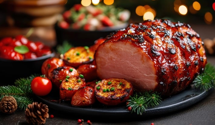Fotografia de uma peça de tender com a fatia da frente cortada mostrando a parte de dentro com pedaços de batatas, cenoura e tomates-cereja assados.