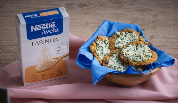 Foto da receita de esfiha de farinha de aveia servida em 4 porções em uma cesta decorada com pano azul em cima de uma mesa de madeira