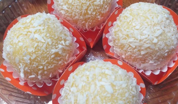 Foto da receita de brigadeiro de milho verde. Observa-se 4 unidades de brigadeiro em forminhas laranjas com estampa de poá branca.