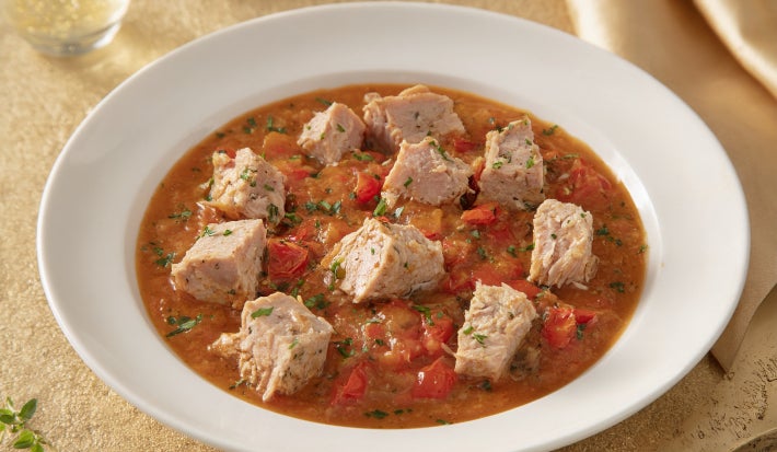 Goulash moderno de atum servido em prato fundo, com cubos de peixe em molho de tomate encorpado e ervas frescas.