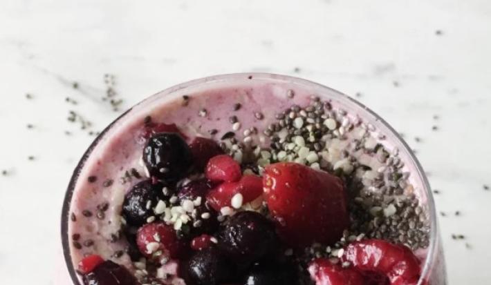 Fotografia em tons de vermelho em uma bancada de mármore branco, com um copo de vidro largo e grande com o smoothie de baunilha com frutas vermelhas dentro dele. Fotografia em tons de vermelho em uma bancada de mármore branco, com um copo de vidro largo e grande com o smoothie de baunilha com frutas vermelhas dentro dele.