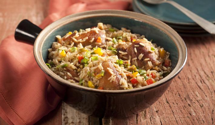 Fotografia em tons de marrom, contém um recipiente redondo com arroz e pedaços de frango