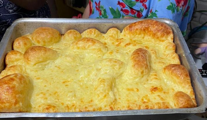 Fotografia de uma forma de alumínio retangular com o pão de queijo montanha russa preenchendo todo o recipiente.