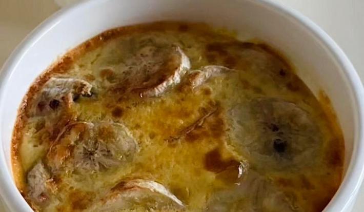 Fotografia de dois ramekins brancos com uma receita de banana cremosa com mel e canela por cima. O ramekin está sobre uma mesa branca.